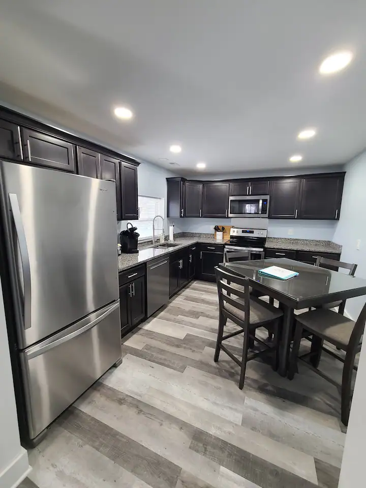 A kitchen with a stainless steel refrigerator, a table, and chairs.