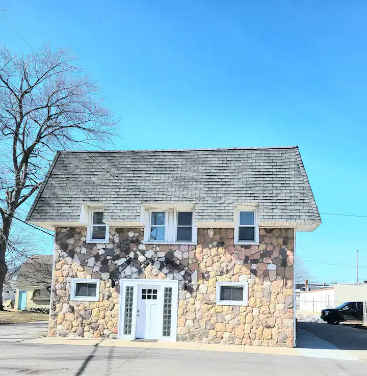 A small stone house with a white door and windows.