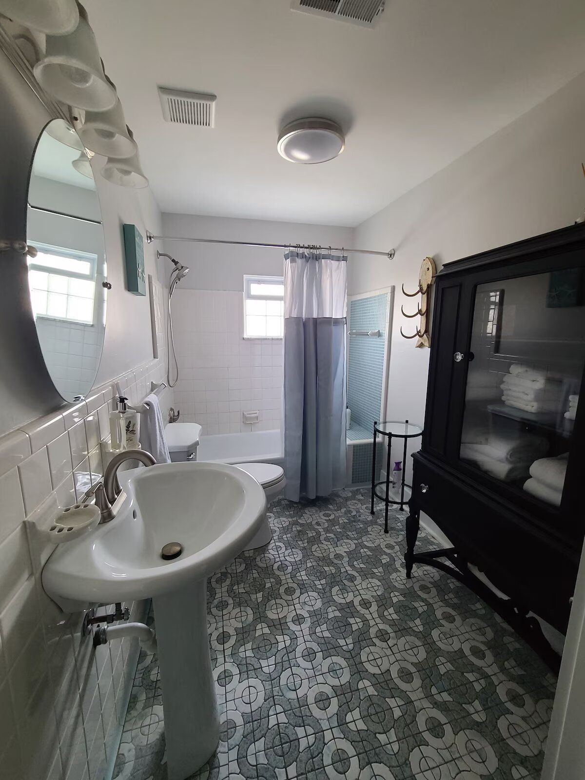 A bathroom with a sink , toilet , shower and mirror.
