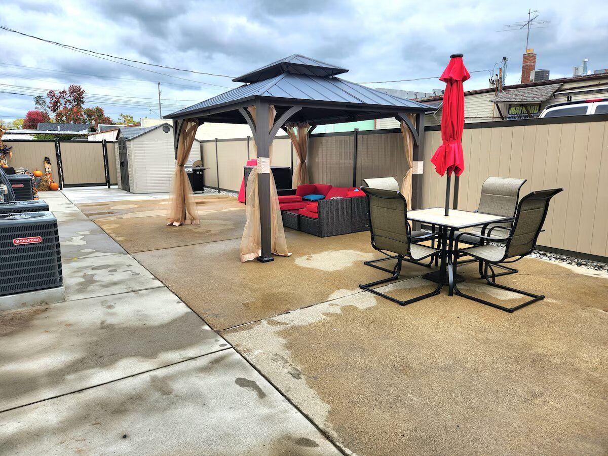 A backyard with a gazebo , table and chairs.