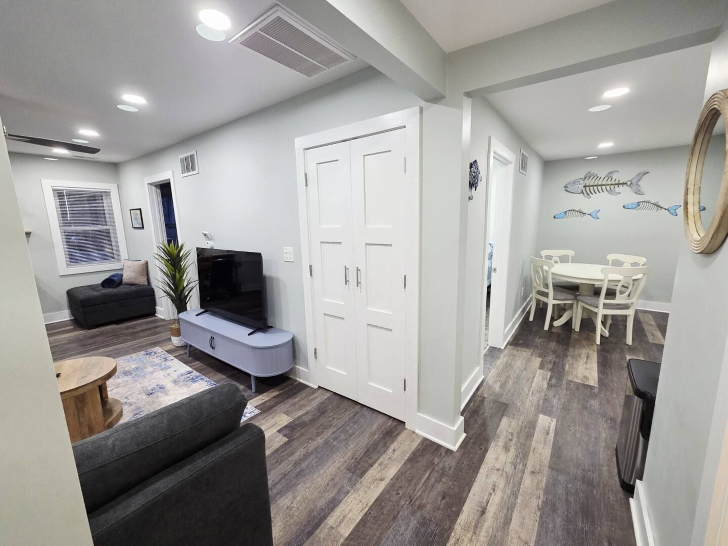 Living room with gray walls, wood-look floor, furniture. Dining area visible, fish art.