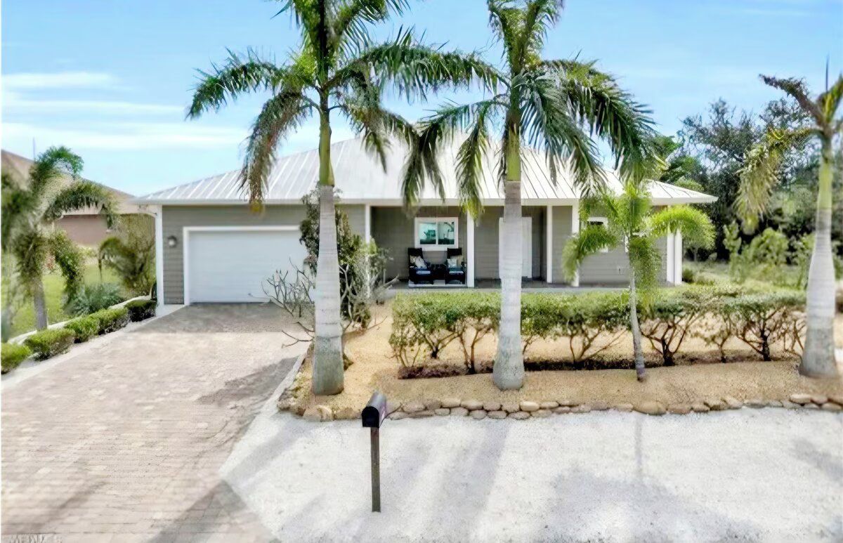 A house with palm trees in front of it and a mailbox.