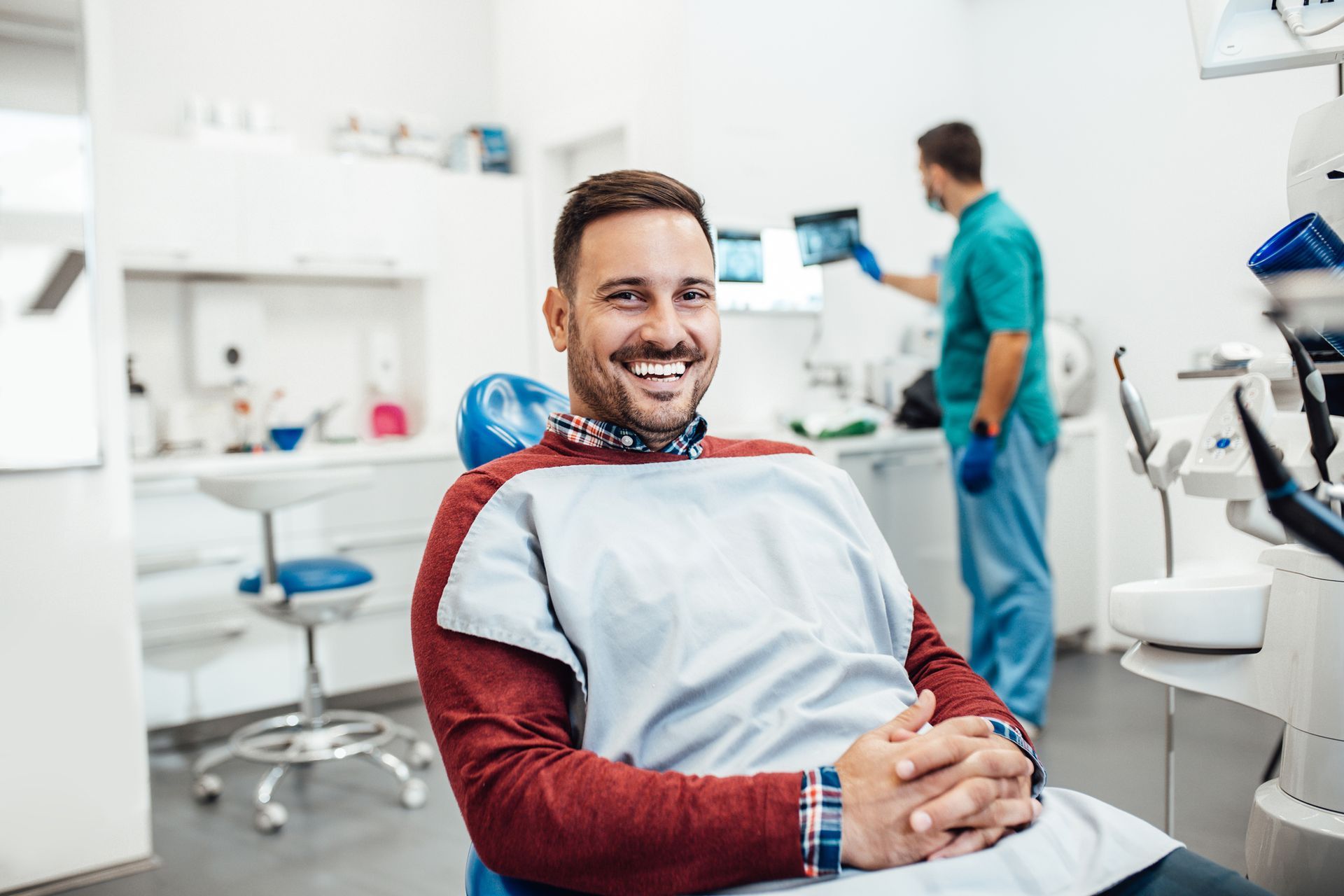 A man is smiling while sitting in a dental chair.