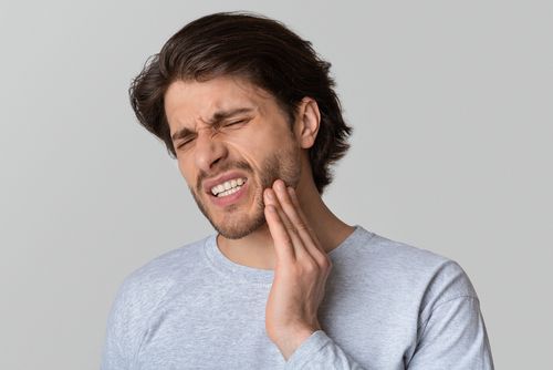 A man is holding his face in pain because of a toothache.