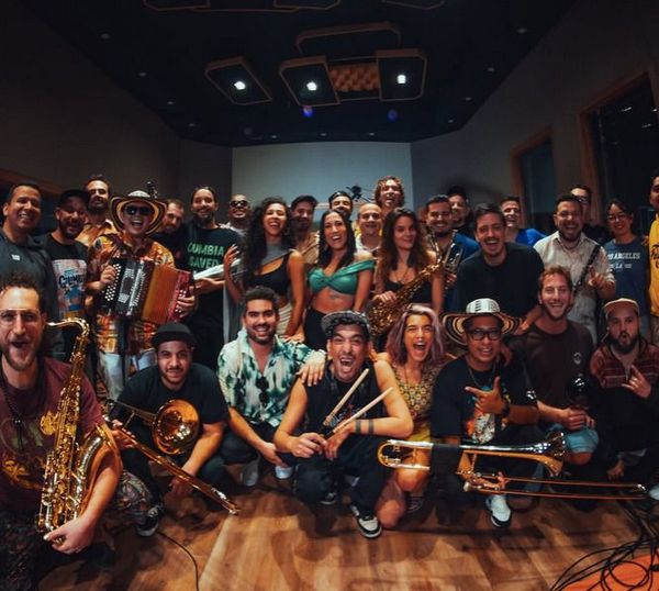 Un gran grupo de músicos posando en un estudio de grabación.