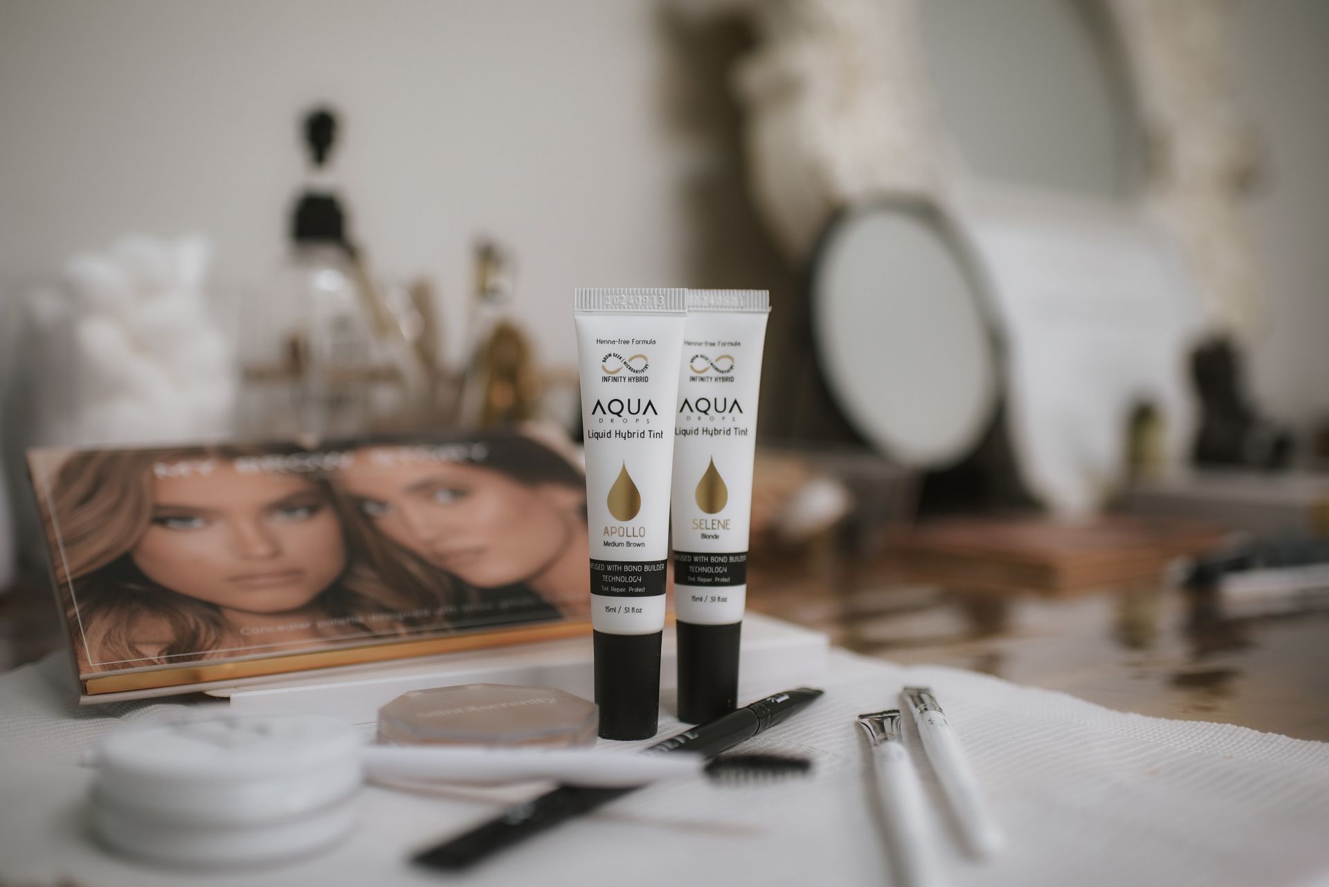 Two tubes of eye cream on a vanity with makeup, a mirror, and a magazine featuring two women.