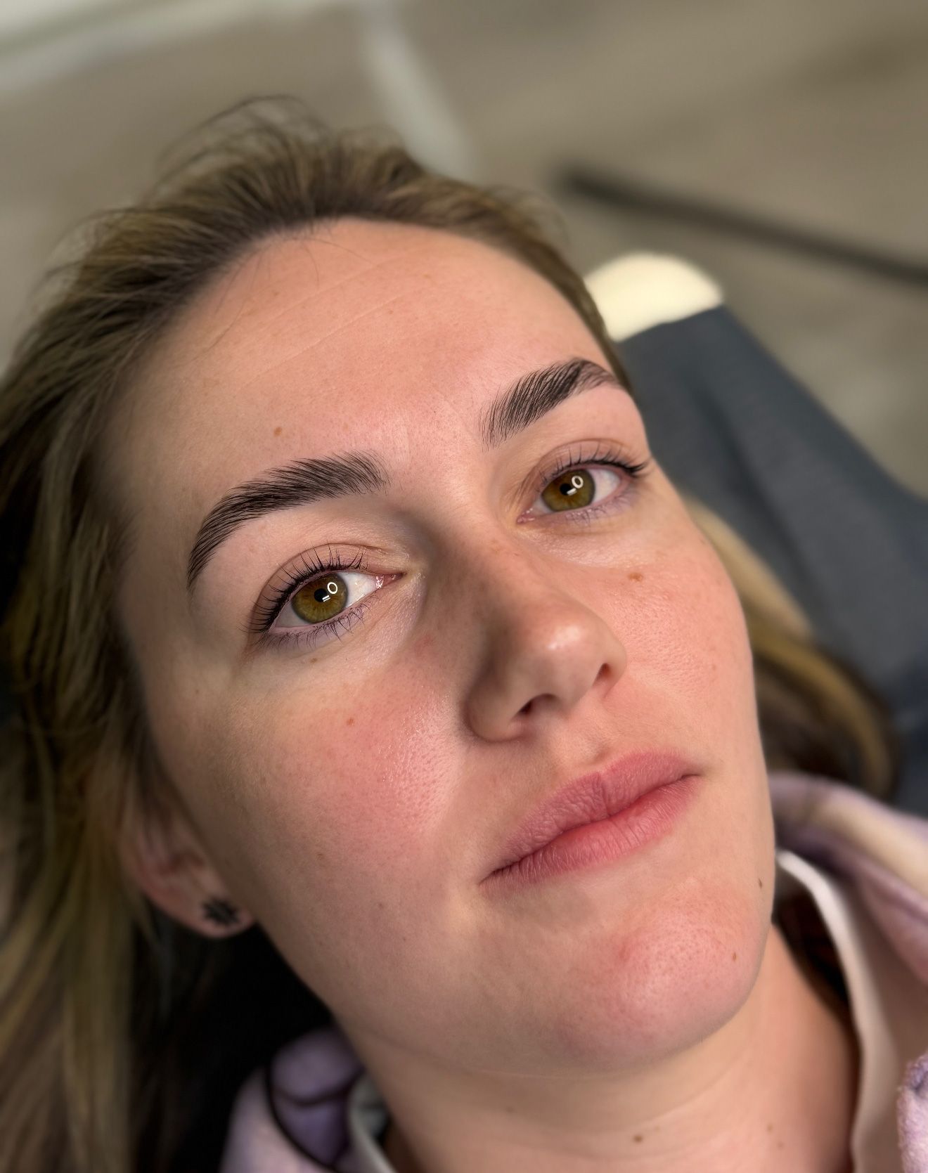 Woman with freshly microbladed eyebrows, brown eyes, and pink lips.