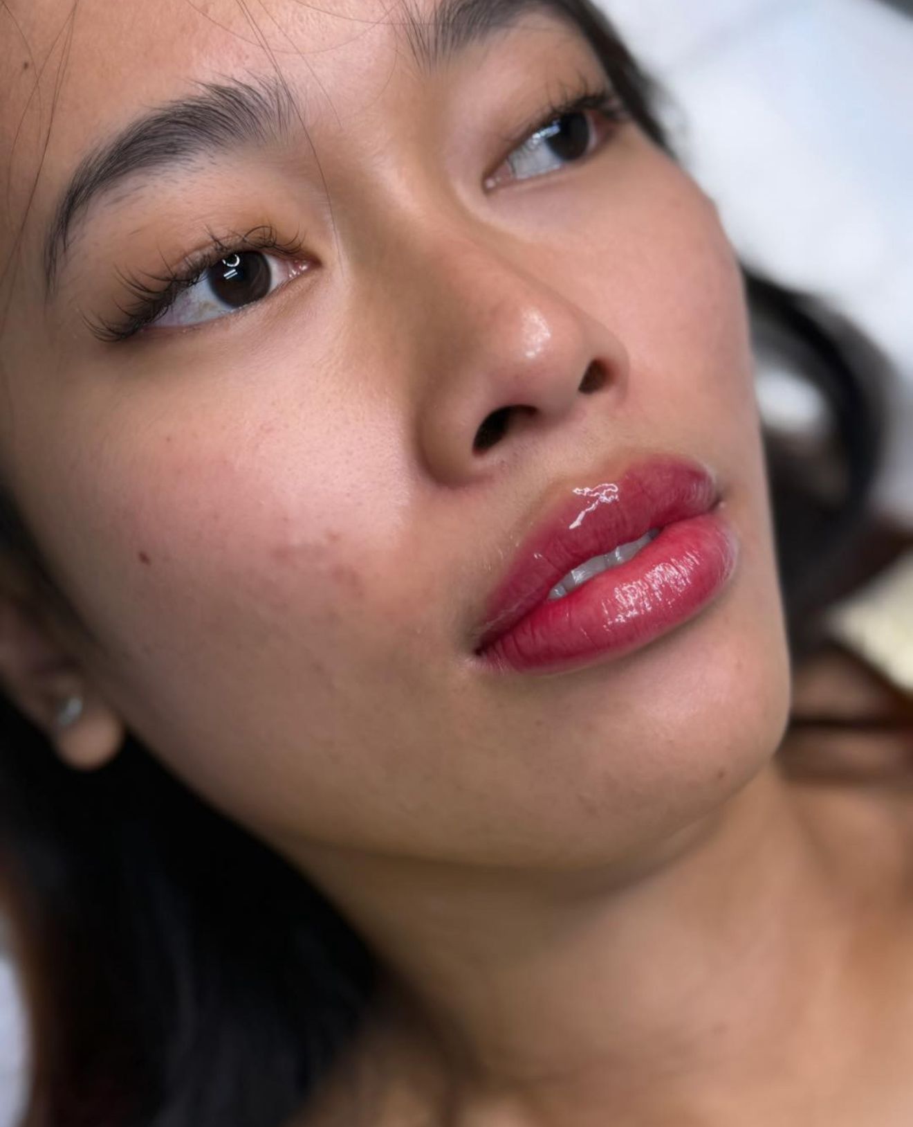 Woman with full, glossy red lips, looking up. Pink cheeks, light skin.