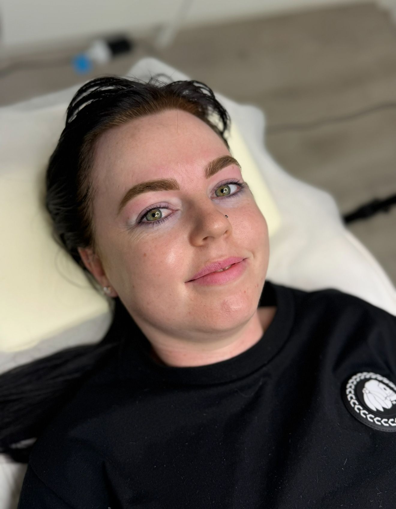 Woman with freshly microbladed eyebrows, light brown in color, smiling at the camera.
