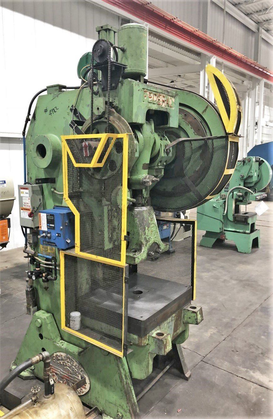 A green and yellow machine is sitting in a warehouse.