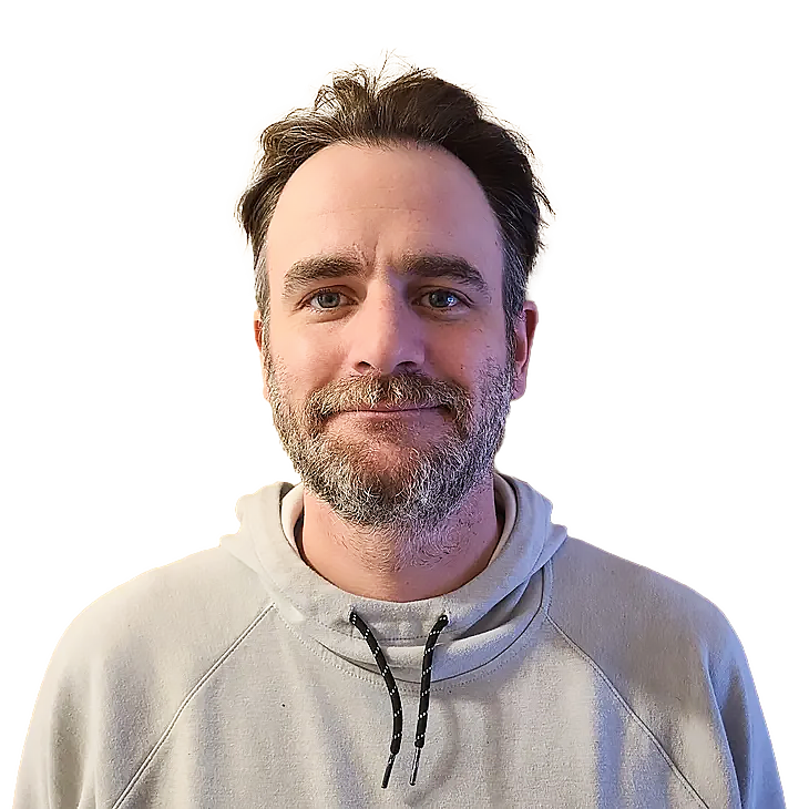 Man with light beard and neutral expression, wearing a light gray hoodie.