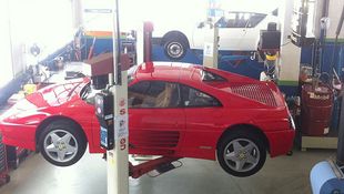 Une voiture de sport rouge est assise sur un ascenseur dans un garage.