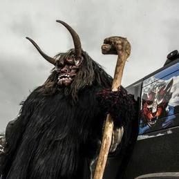 Un monstre avec des cornes et une canne se tient à côté d'un camion.