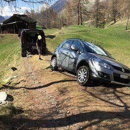 Une voiture est coincée dans la boue sur un chemin de terre.