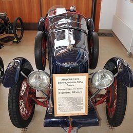 Une voiture de course bleue et rouge avec une pancarte attachée.