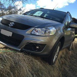 Une suzuki sx4 est coincée dans l'herbe dans un champ.