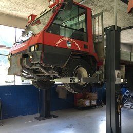 Un camion rouge est assis au sommet d'un ascenseur dans un garage.