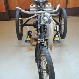 Un vélo à trois roues repose sur un sol en béton.