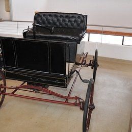 Une vieille calèche est posée sur le sol dans une pièce.