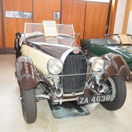 Une vieille voiture est garée dans une pièce à côté d'une voiture verte.