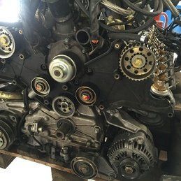 Un gros plan d'un moteur de voiture posé sur une palette en bois.