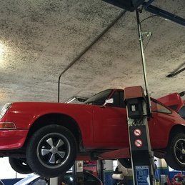 Une voiture rouge est assise au sommet d'un ascenseur dans un garage.