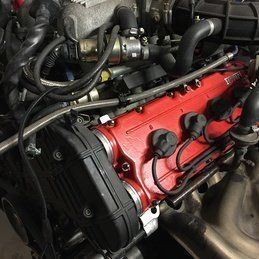 Un gros plan d'un moteur de voiture avec un couvercle rouge.