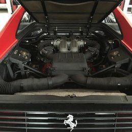 Le moteur d'une Ferrari rouge avec le capot relevé.