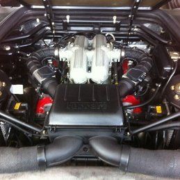 Un gros plan du moteur d'une voiture avec le capot relevé.