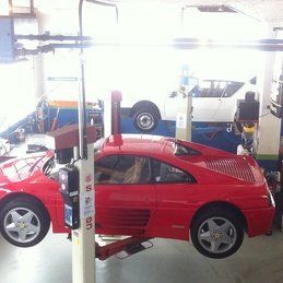 Une voiture de sport rouge est assise sur un ascenseur dans un garage.