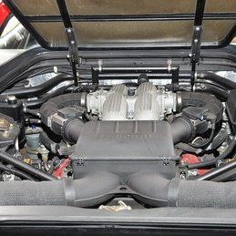 Un gros plan d'un moteur de voiture avec le capot ouvert.