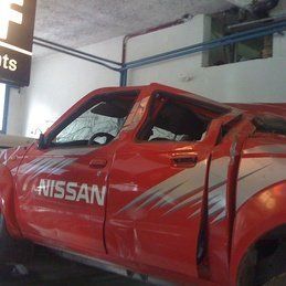 Un camion Nissan rouge est garé dans un garage.