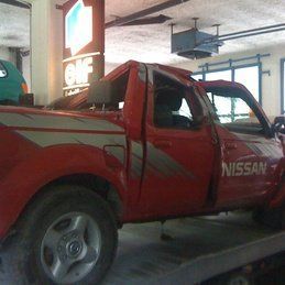 Un camion Nissan rouge est garé dans un garage