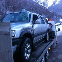 Un SUV argenté est remorqué par une dépanneuse.