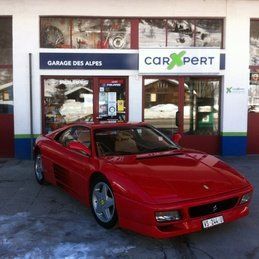 Une voiture rouge est garée devant un garage.