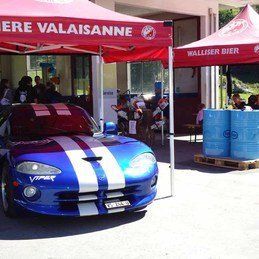 Une Dodge Viper bleue et blanche est garée sous une tente rouge.