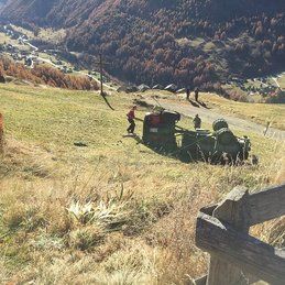 Un tracteur est assis au sommet d'une colline couverte d'herbe.
