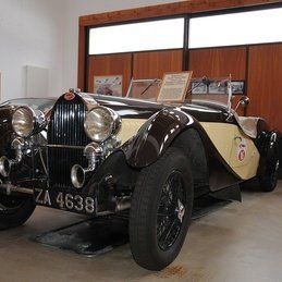 Une vieille voiture est garée dans un garage à côté d'une fenêtre.