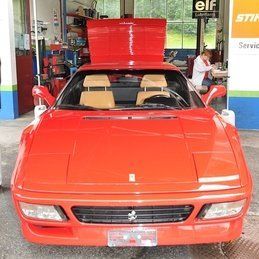 Une Ferrari rouge avec le capot relevé est garée dans un garage.