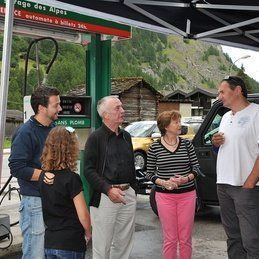 Un groupe de personnes se tiennent devant une station-service et se parlent.