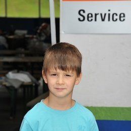 Un jeune garçon se tient devant un panneau de service.