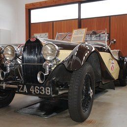 Une voiture vintage noire et blanche est garée dans un garage.