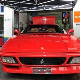 Une ferrari rouge est garée devant un garage.