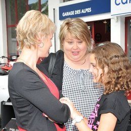 Trois femmes se tiennent côte à côte devant une pancarte du garage des alpes.
