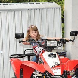 Une petite fille est assise sur un VTT rouge avec une chemise Hello Kitty.