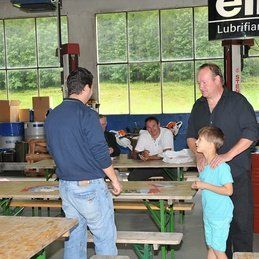 Un groupe de personnes se tient autour de tables dans une pièce.