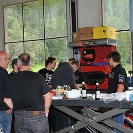 Un groupe d'hommes se tient autour d'une table dans un garage.