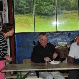 Un groupe de personnes sont assises à une table en train de manger de la nourriture.