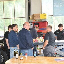 Un groupe d'hommes se tient autour d'une table dans un garage.