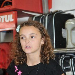Une jeune fille se tient devant une pancarte motul.